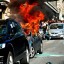 Italy: Protesters look at a parked car on fire during a demonstration, in downtown Rome after tens of thousands marched today as part of a global day of protests