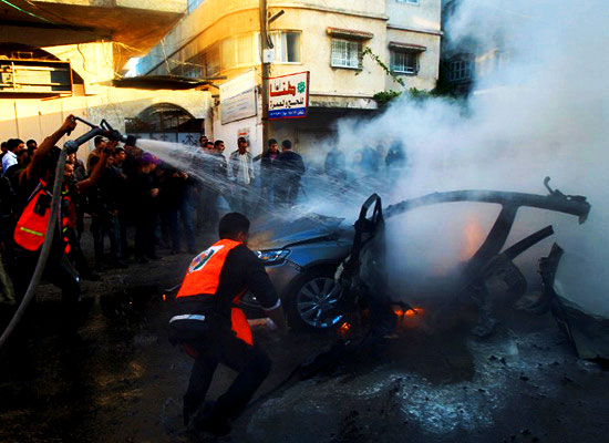 Palestinians extinguish fire from the car of Ahmaed Jaabari