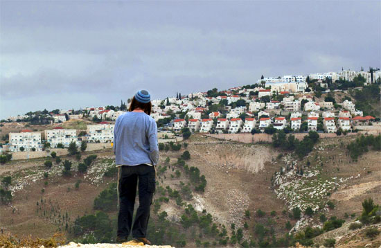 A Jewish settler looks at the West bank settlement of Maaleh Adumim, from the E-1 area on the eastern outskirts of Jerusalem, Wednesday, Dec. 5, 2012.